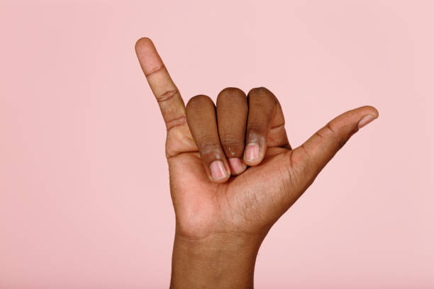 African-American person shows shaka gesture to cheer up on pink stock photo