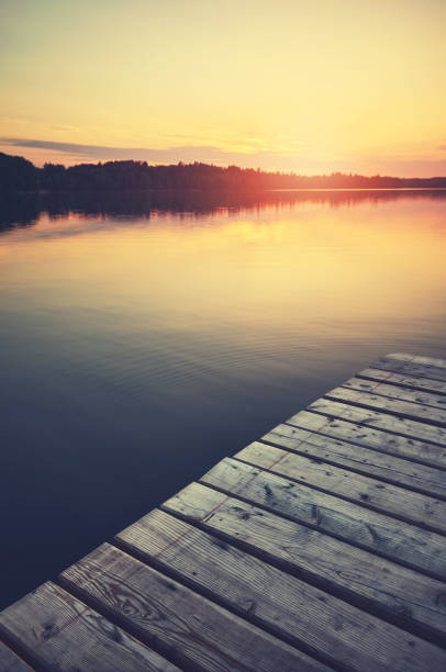 istock Sunset over still lake, wooden pier in foreground. 1343489018