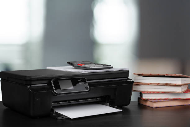 istock Compact home printer on desk with books against blurred background 1343490234