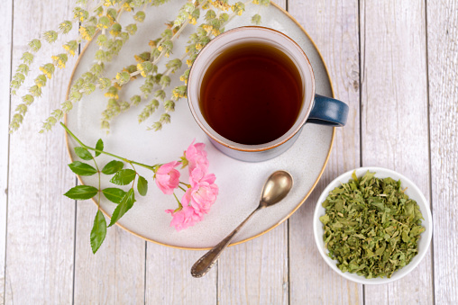 Green tea or herbal tea with cup, plate and dry herbs