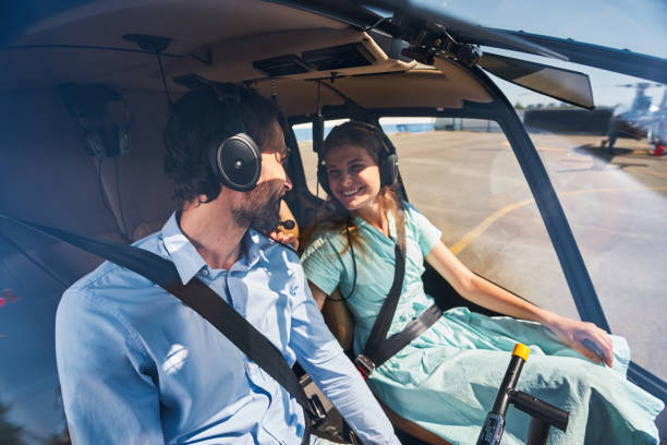 Couple seated in private chopper before take-off High-spirited Caucasian female passenger sitting in front seat next to male pilot in helicopter cockpit helicopter seat stock pictures, royalty-free photos & images