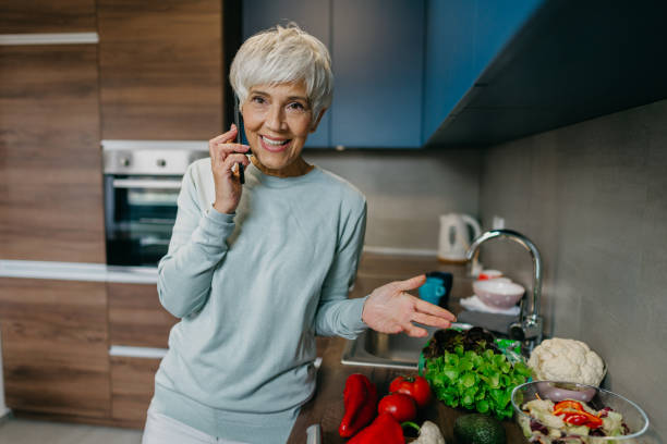 istock Woman using laptop and make a phone call in the kitchen 1343497285