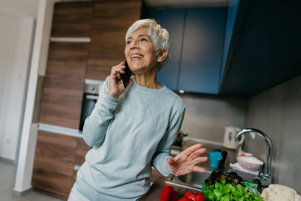 istock Woman using laptop and make a phone call in the kitchen 1343497290
