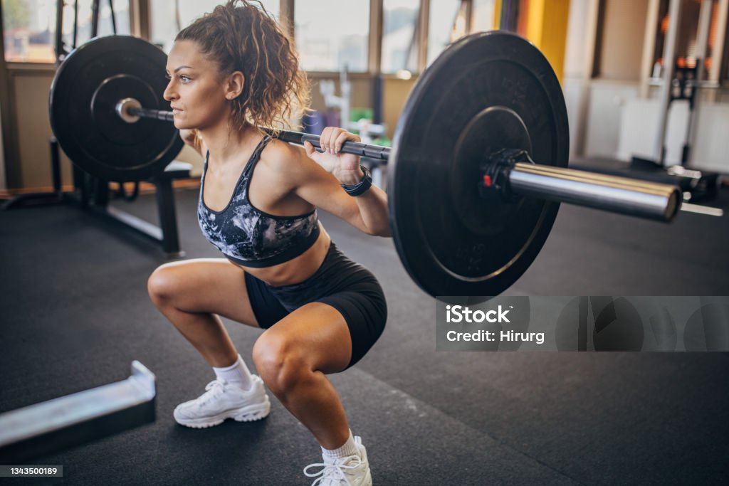 Woman exercising with weights One woman, young woman exercises with weights in gym. Barbell Stock Photo