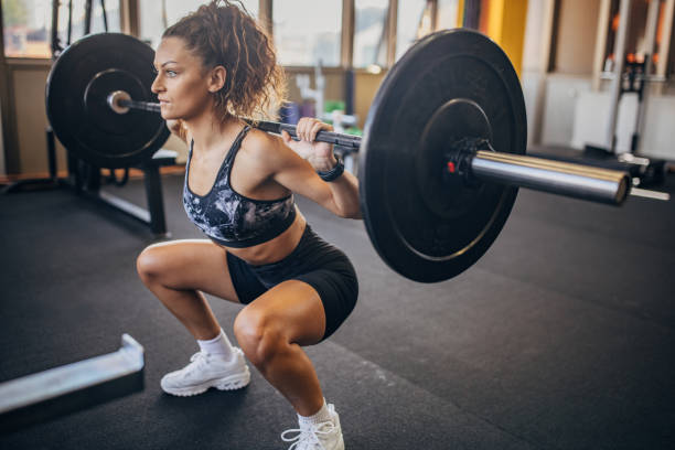Woman exercising with weights One woman, young woman exercises with weights in gym. squatting position photos stock pictures, royalty-free photos & images