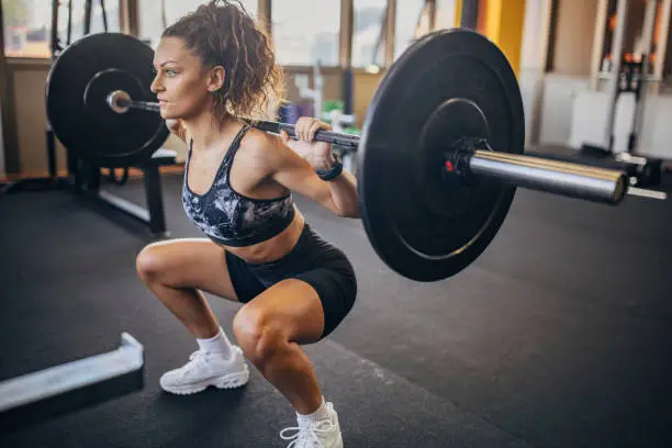 One woman, young woman exercises with weights in gym.