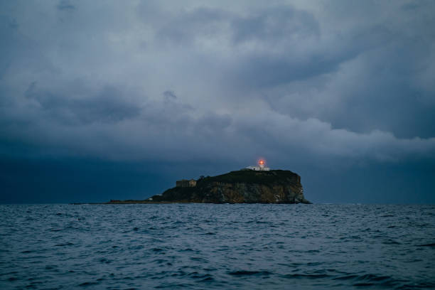 faro en un mar brumoso muestra la dirección: concepto de soledad y esperanza - arrival beacon blue nautical vessel fotografías e imágenes de stock