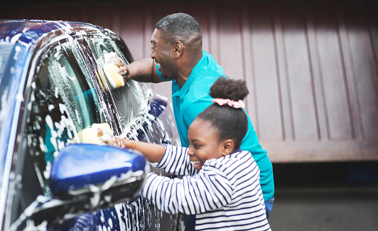 Foto de un padre y su hija lavando su auto afuera photo