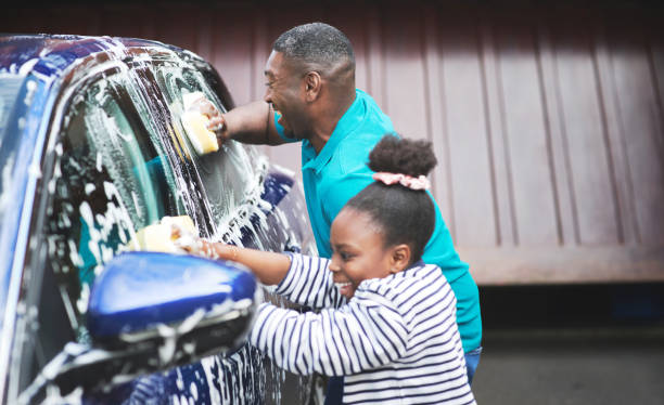 foto de un padre y su hija lavando su auto afuera - lavar fotografías e imágenes de stock