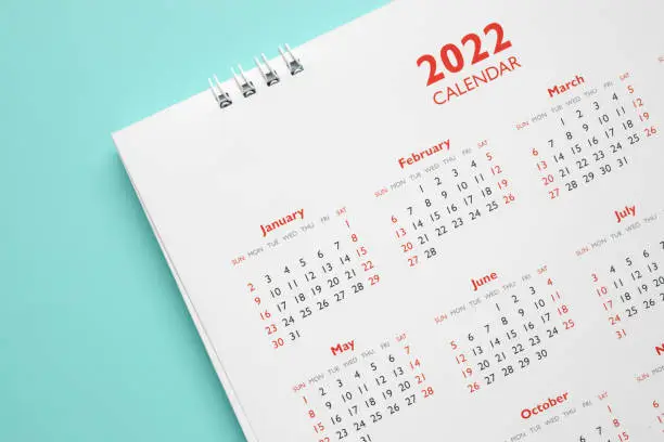 Photo of 2022 calendar page on blue background business planning appointment meeting concept