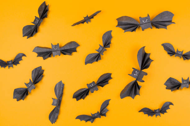 Many bats made of paper on an orange background. Flat lay. The concept of Halloween, and holiday decorations Many bats made of paper on an orange background. Flat lay. The concept of Halloween, and holiday decorations. flock of bats stock pictures, royalty-free photos & images