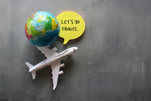 Travel and vacation concept. Top view of toy plane, earth globe and note paper with text LET'S GO TRAVEL. Copy space for text.