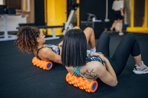 Two women, woman exercises with her female personal trainer in gym.