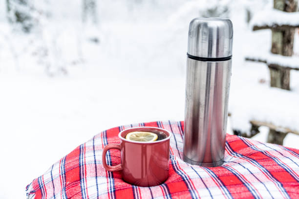 istock Winter scene - mug with hot drink and thermos on the table covered with plaid. 1343503230