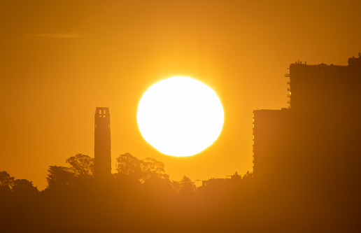 Telephoto of the Sun rising next to Coit Tower in San Francisco, California, USA
