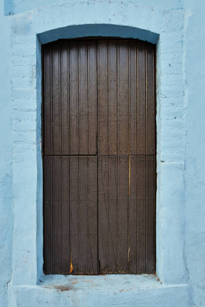 Sky blue facade with a chocolate colored wooden window on a frame stock photo