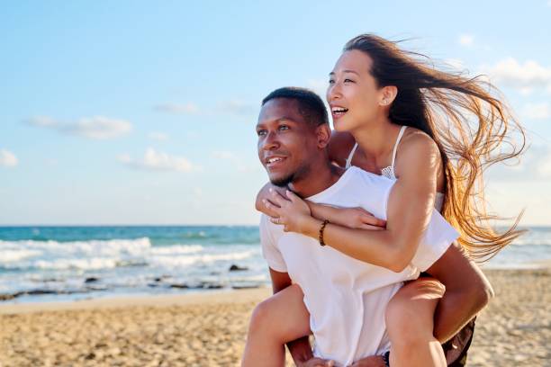 молодая красивая веселятся пара на морском фоне - couple young adult african descent multi ethnic group стоковые фото и изображения