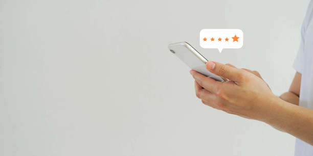close up on customer man hand pressing on smartphone screen with  five star rating feedback icon and press level good rank for giving best score point to review the service , technology business concept
