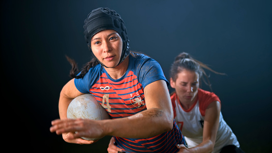 Female rugby player tackling her opponent running with the ball.