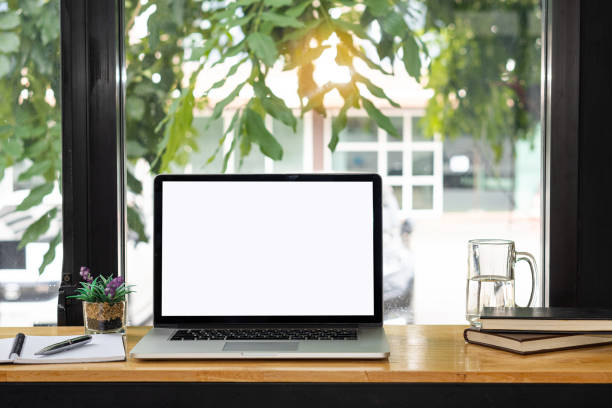 istock Laptop computer with white screen on table with notebook and pen and mug. Coffee shop concept. 1343513984