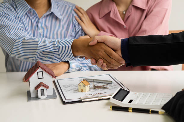 The sales representative shakes hands and hands the keys to the new homeowner after the sale contract is complete. A businessman offers a contract to purchase a house for the purchase of real estate or an apartment to customers. el representante de ventas estrecha las manos y entrega las llaves al nuevo propietario después de que se complete el contrato de venta. un hombre de negocios ofrece un contrato para comprar una casa para la compra de bienes raíces o un apartamento a los