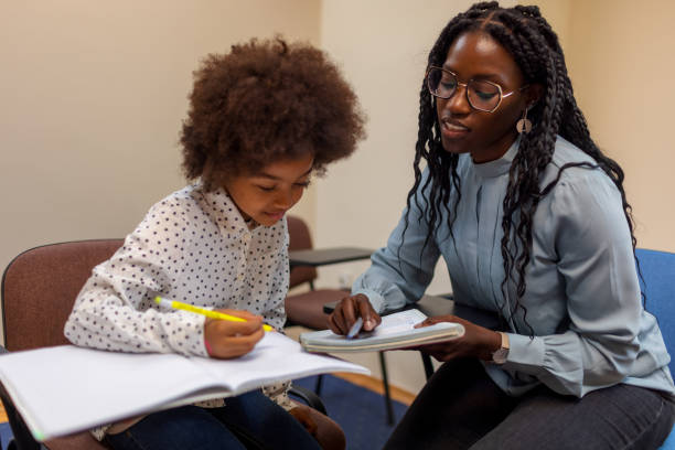 Un enseignant noir aide une petite fille à écrire et à lire - Photo