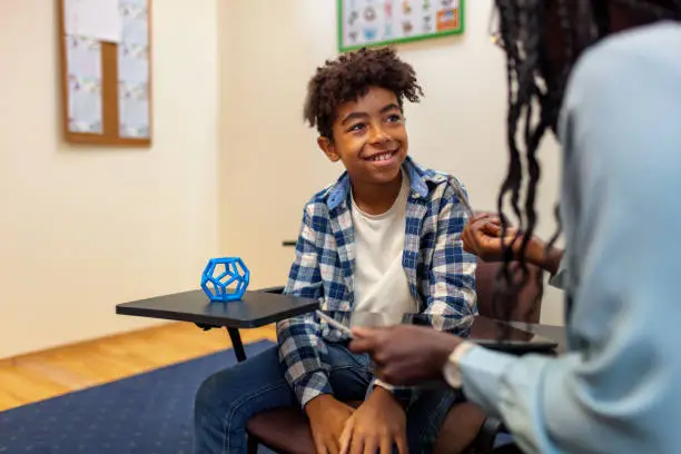 Black teacher works with male student in the classroom. One on one consultation.