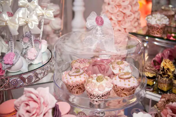 Delicious desserts at the wedding candy bar in the buffet area: muffins decorated with angels, cameo, sugar rosebuds and gold dye.