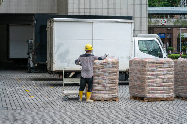 A forklift operator loading or unloading goods inside a truck at a warehouse dock. The scene highlights logistics and industrial work.