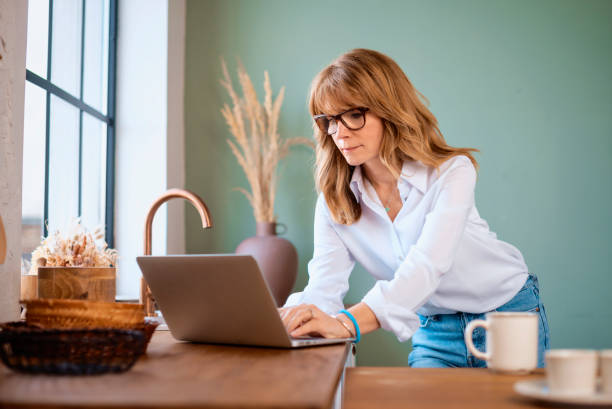 istock Businesswoman standing in the kitchen and using laptop while working from home 1343517662
