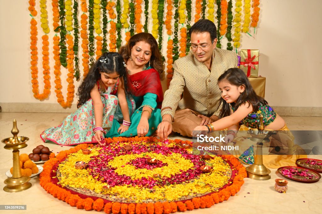 Family in tradional clothes decorating flower rangoli on diwali festival Family in Tradional clothes decorating flower Rangoli on floor on the occasion of  diwali festival Diwali Stock Photo