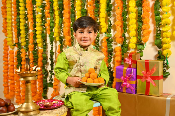 istock Small boy holding mithai plate in tradional clothes looking at the camera 1343519366