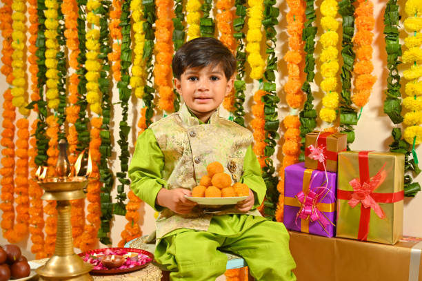 istock Small boy holding mithai plate in tradional clothes looking at the camera 1343519398