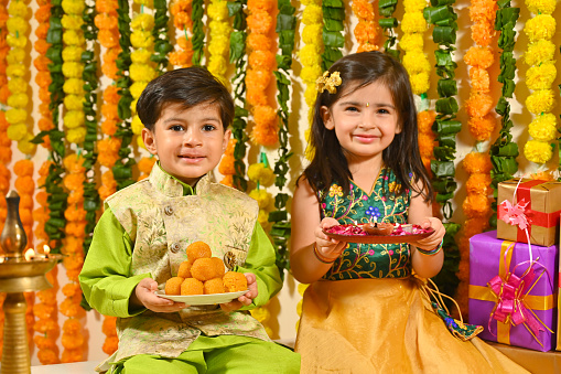 Small kids in Tradional clothes holding Diwali plates looking at the camera and smiling on the occasion of festivities