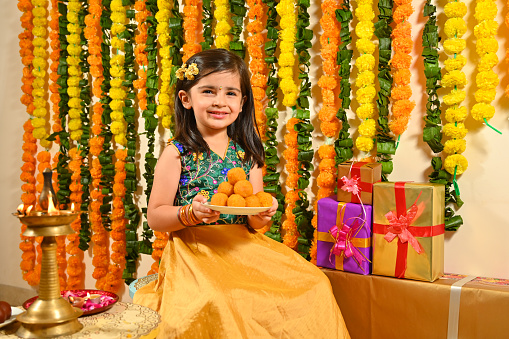 Small girl in Tradional clothes holding mithai plate in hand on the occasion of festivals