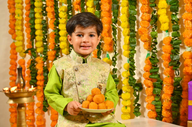 istock Small boy holding mithai plate in tradional clothes looking at the camera 1343519792