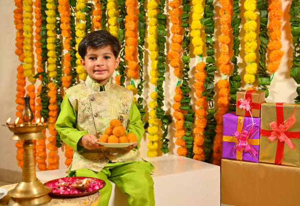 istock Small boy holding mithai plate in tradional clothes looking at the camera 1343519936