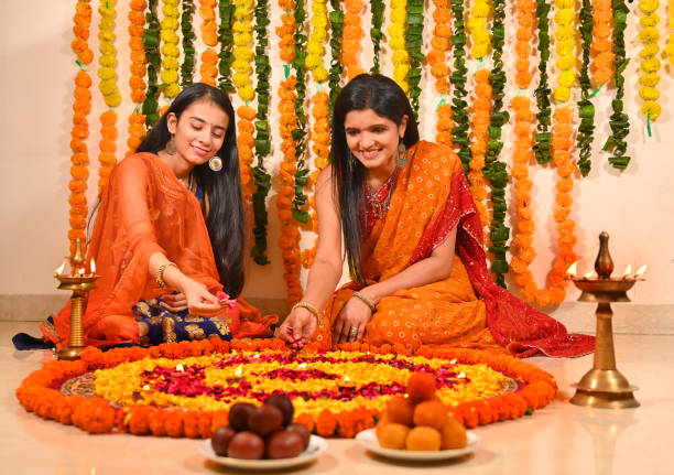 istock Mother with daughter decorating flower rangoli on floor 1343520282