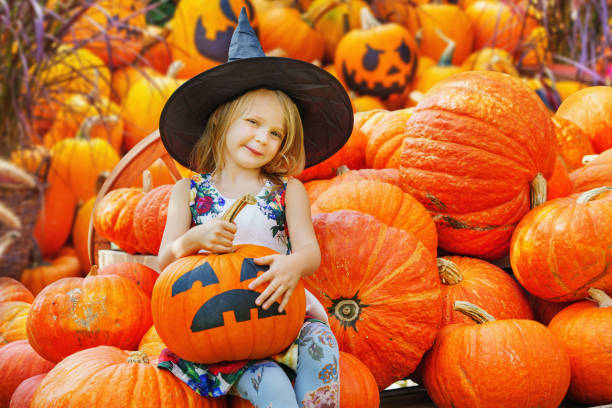 una ragazza carina travestita da strega che seleziona la zucca perfetta - pumpkin child little girls pumpkin patch foto e immagini stock