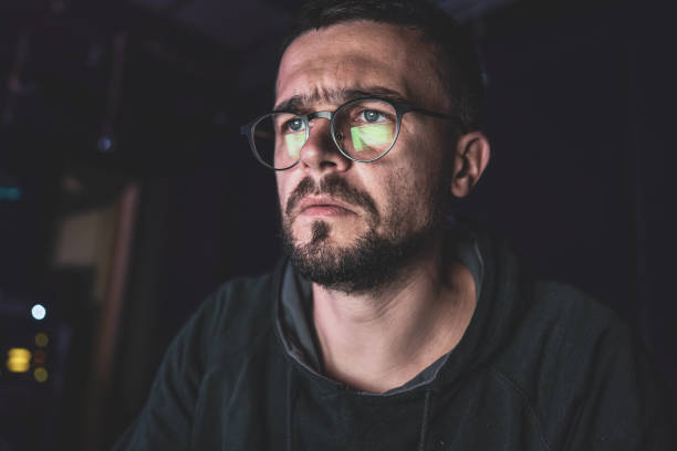 istock A man wearing glasses stares intently at a computer screen late at night. 1343528097