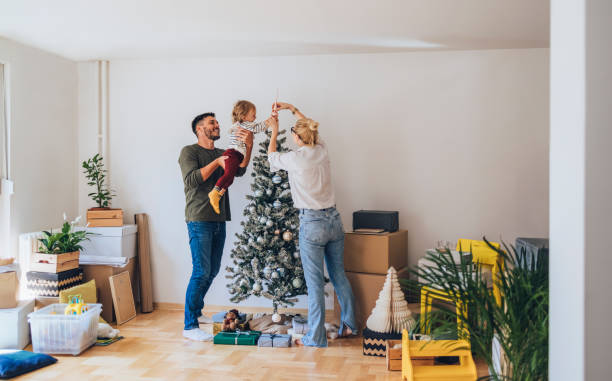 feliz familia decorando el árbol de navidad en un nuevo hogar - christmas home fotografías e imágenes de stock