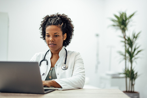 Smiling doctor using laptop while working in private practice.