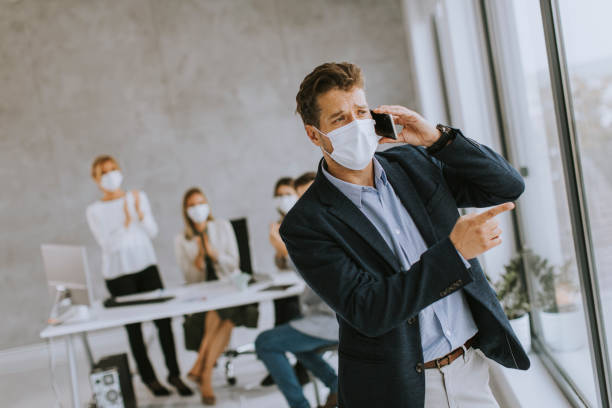 istock Young business man using mobile phone while wear protective masks to prevent  corona viruus at office space 1343539584