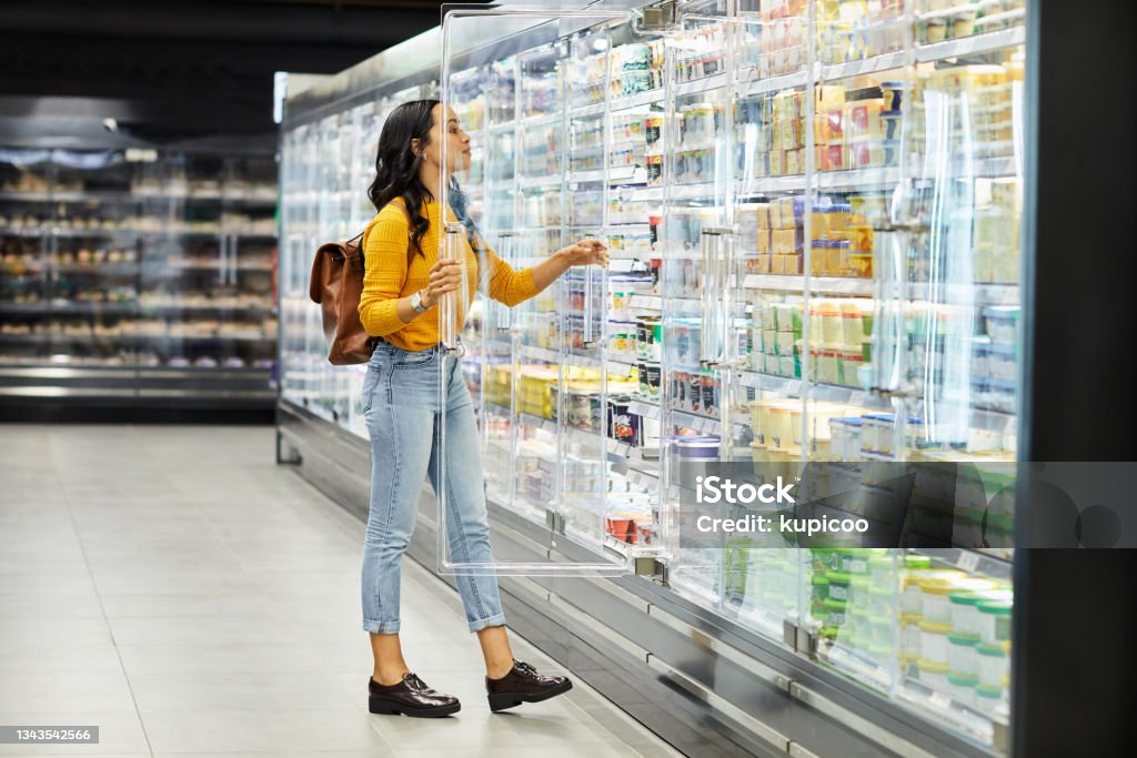 Shot of a young woman shopping for groceries in a supermarket When in Rome, eat your weight in gelato Supermarket Stock Photo