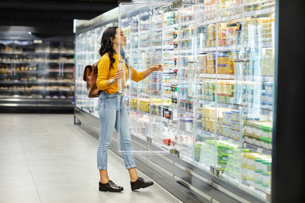 zdjęcie młodej kobiety robiącej zakupy spożywcze w supermarkecie - chłodnictwo zdjęcia i obrazy z banku zdjęć