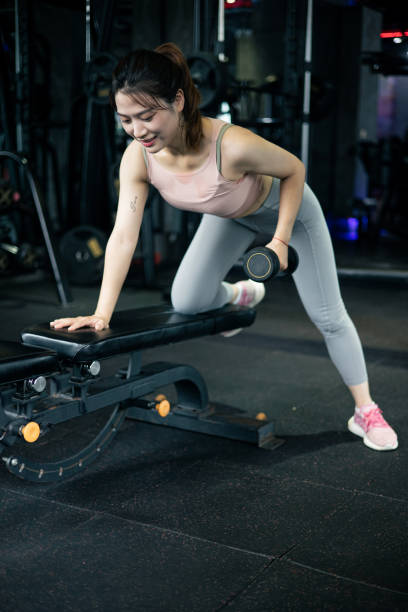 jeunes femmes utilisant un haltère dans le gymnase - weight bench flash photos et images de collection