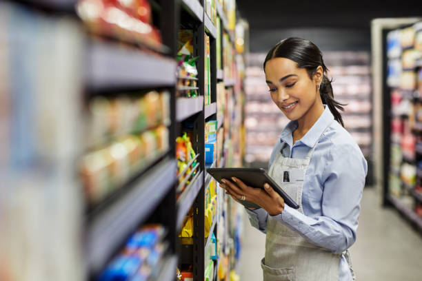 scatto di una giovane donna che usa un tablet al lavoro in un supermercato - smart mobile foto e immagini stock