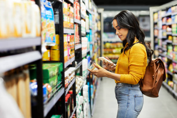 Shot of a young woman shopping for groceries in a supermarket When the going gets tough, the tough eats Cherry retail technology stock pictures, royalty-free photos & images
