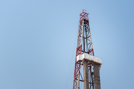 Derrick structure of oil drilling rig with daytime sky background. Heavy industrial equipment and object photo.