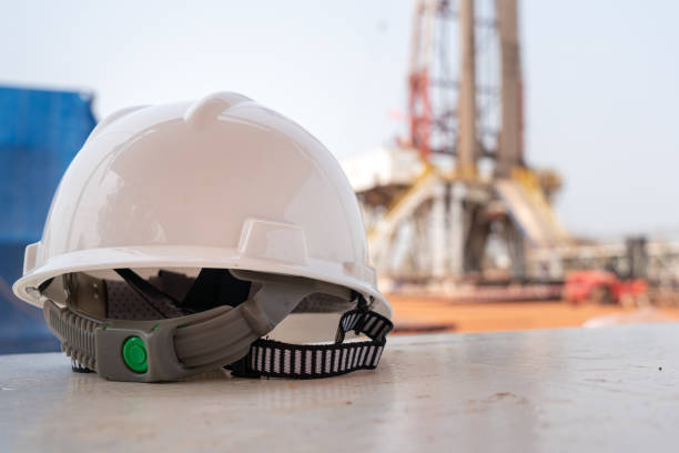 istock A white safety hardhat with drilling rig background. 1343545806